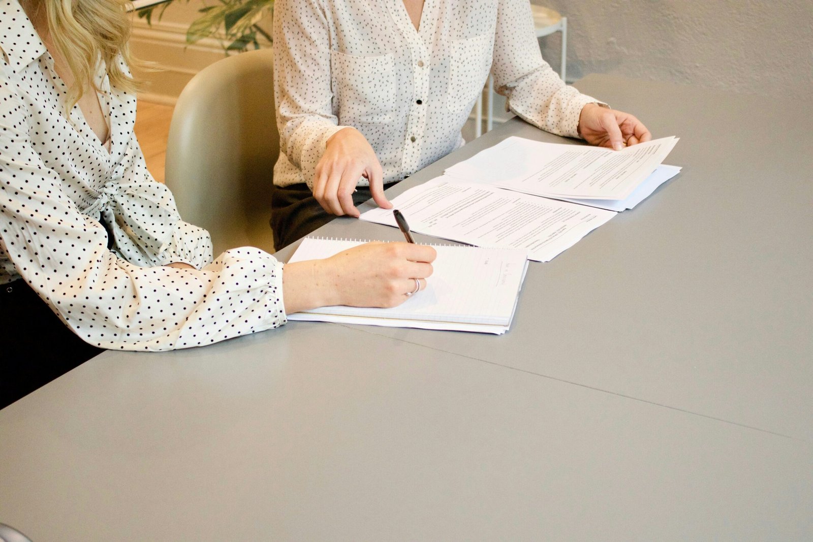 Someone filling out paperwork at a desk surrounded by files.
